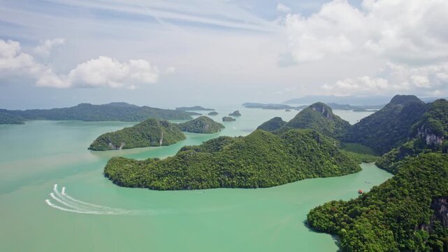 Aerial landscape of Langkawi's lush limestone islands surrounded by turquoise Andaman Sea waters while jet skis create dynamic wake patterns through the tropical archipelago.