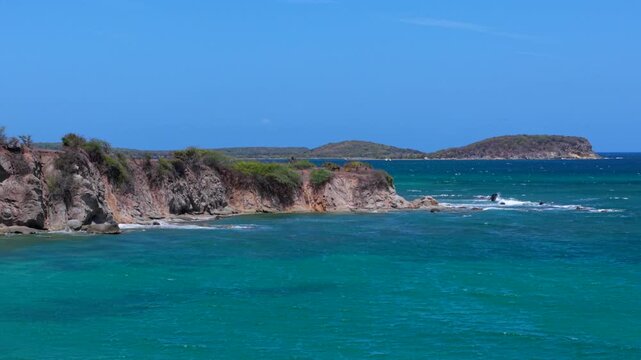 Approaching drone fly toward rugged tropical shore with rocky cliffs of Vieques surrounded by vivid turquoise Caribbean Sea, Puerto Rico