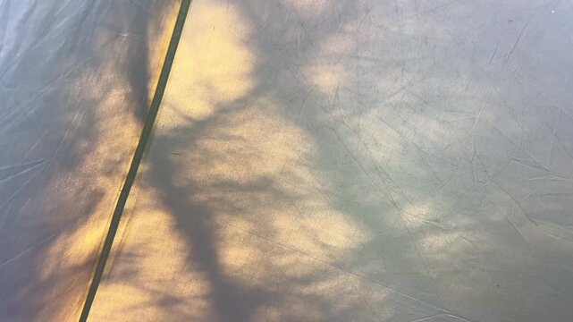 Natural light and tree shadows creating patterns on a camping tarp.