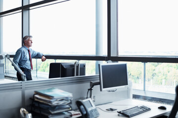 Fototapeta premium Mature, businessman and thinking with window in office for corporate ambition or improvement. Thoughtful, man or employee contemplating with reflection with space or business opportunity in workplace