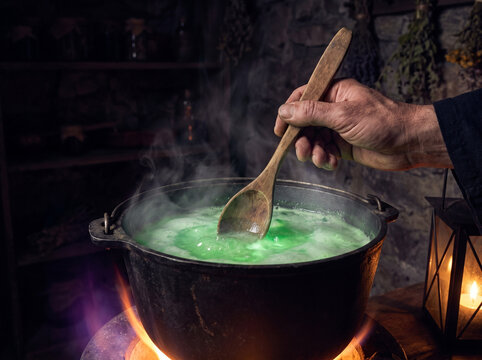 Person stirring green potion in cauldron with wooden spoon at night  