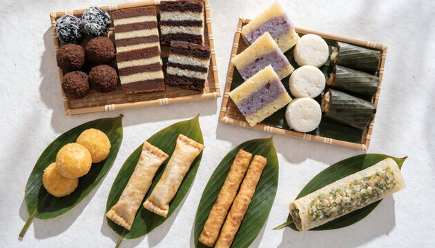 Variety of Traditional Indonesian Snacks and Jajanan Pasar Served on Green Leaves and Bamboo Trays