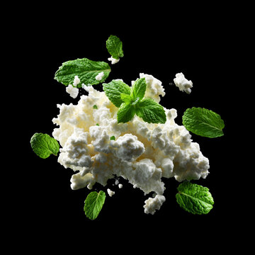 Fresh cottage cheese with green mint leaves, isolated on black background, concept of healthy food and freshness