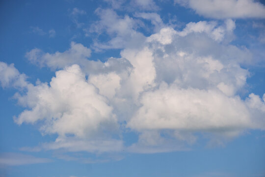 Large soft white and grey cumulus clouds rolling across a bright blue sky