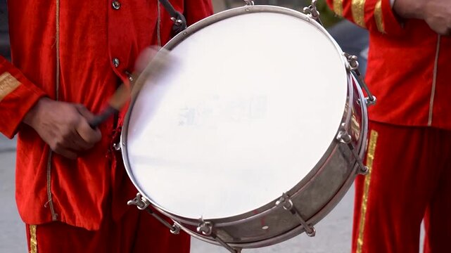 Musician Playing a Traditional Drum in Bright Red Uniform