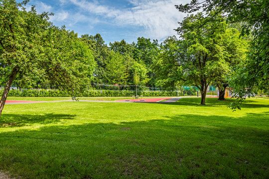Lush green city park with a running track and trees on a sunny day