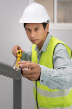 inspector or engineer is inspecting construction and quality assurance check dimension of house by using a tape measurement. Engineers or architects or contactor work to build the house before sell.