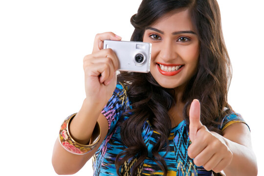 Young woman taking photograph with camera and showing thumbs up