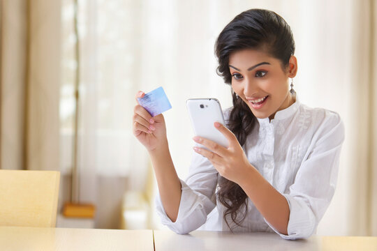 Young woman using phone and holding a credit card