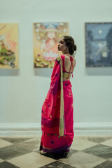 Fototapeta premium Elegant Portrait of an Indian Woman Wearing a Pink Saree Inside an Art Gallery