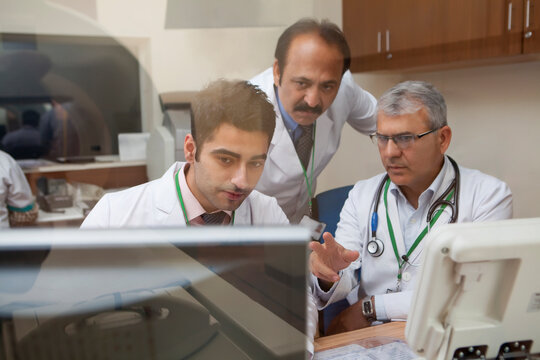 Doctors looking at CT scan on computer screen