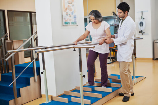 Physiotherapist helping patient to walk