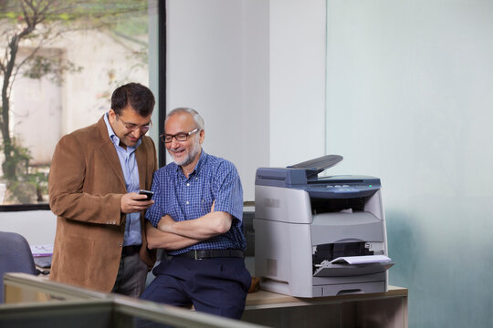 Two male executives looking at sms on mobile phone