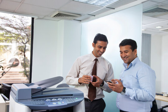Two male executives looking at sms on mobile phone
