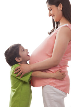 Boy resting chin on belly of pregnant mother