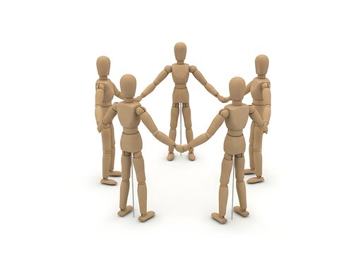 Group of wooden figures forming a circle with joined hands symbolizing unity and teamwork