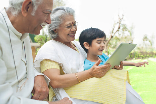 Grandparents showing digital tablet to grandson