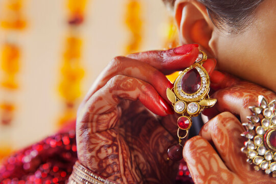 Close-up of a brides hands putting on an earring