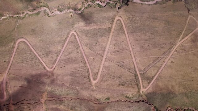 Topdown 4K drone aerial view of the winding mountain road to Iruya, Jujuy, Argentina. Scenic zigzag route crossing the Andes with dramatic landscapes and remote valleys.