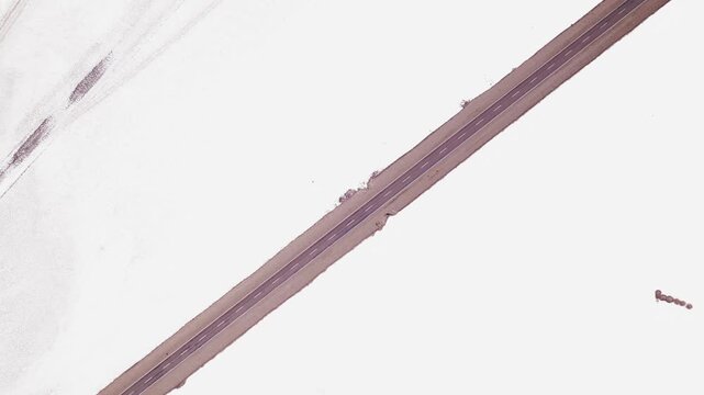 4K drone aerial view of Salinas Grandes in Jujuy, Argentina. One of the largest salt flats in the country, with endless white salt plains crossed by a road through the high altitude Andean Puna.