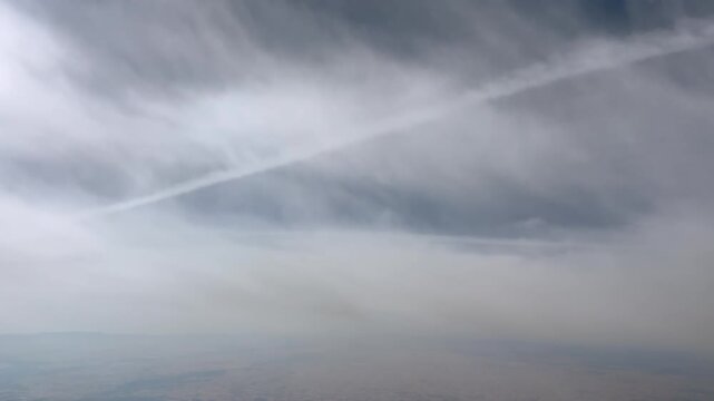 An immersive jet pilot view from cockpit flying in the stratosphere between ethereal clouds and under other jet contrails.