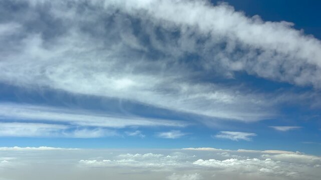 An immersive pilot&rsquo;s view from a jet copckpit flying under jet contrails, and over an endless sea of stratus clouds in a blue sky.