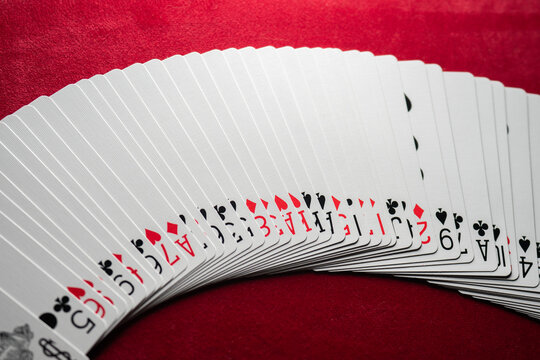Fanned deck of playing cards arranged on red felt table