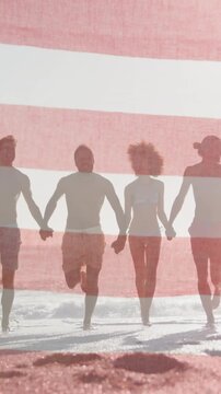 American flag waving against group of friends holding hands running together on the beach