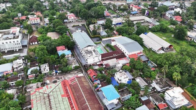 Cinematic aerial flyover showcasing Hotel Prince surrounded by Alappuzha's green neighborhoods, coconut palms, and urban landscape. An ideal stock video for travel, hotel, and promotional productions.
