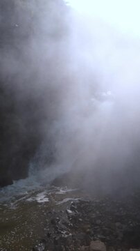 A mist of volcanic waterfalls rises in the rocky canyon