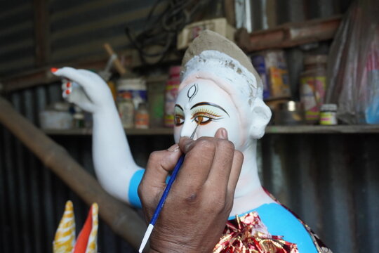 Artisan painting the eyes of a traditional clay goddess idol