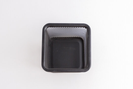Empty black square metal mesh pen holder isolated on a white background