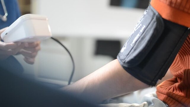 Doctor checks patient's blood pressure with cuff and stethoscope in a medical