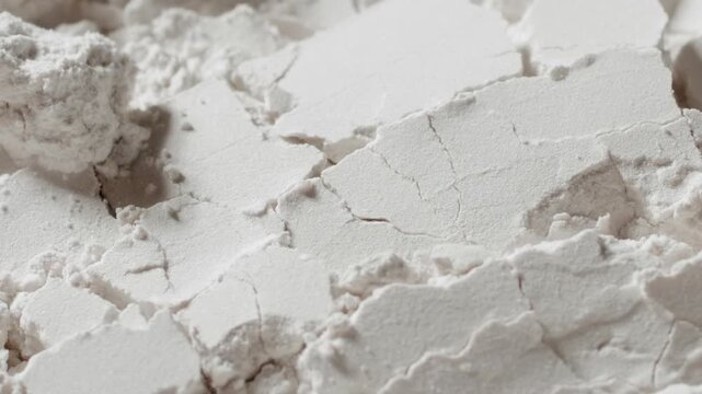 High-magnification slow-motion shot of white powder surface being blown with a strong air stream, breaking its structure and chipping it into small pieces | Titanium dioxide commercial concept