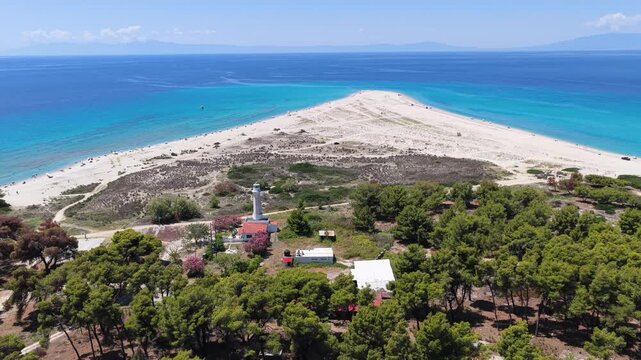 Lighthouse and pine forest beside a sandy beach peninsula framed
