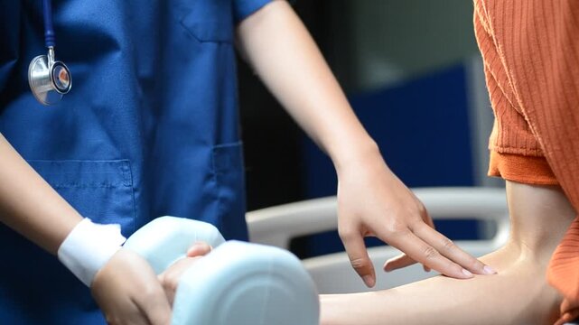 Physical therapist guides male patient using dumbbells for strength training. Person works out arm muscles in clinic. Patient performs rehabilitation exercises for recovery and mobility.