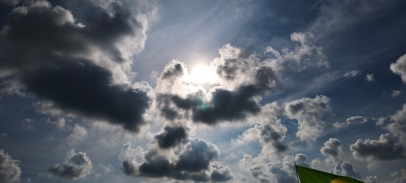 A dynamic sky filled with clouds of varying densities, illuminated by sunlight breaking through with radiant rays. 