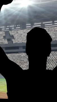 Animation of silhouette of male athlete cheering with arms in air over sports stadium