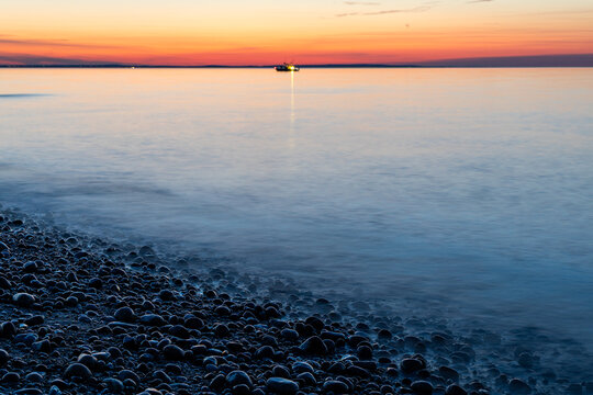 Rocky shore with a distant boat at sunset