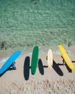 Four surfers with colorful boards at the shoreline