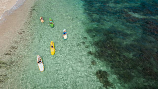 Friends relaxing on surfboards in clear ocean