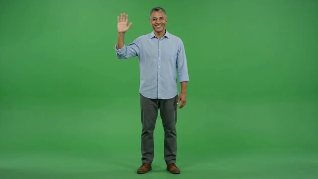 Friendly man waving hello on a green screen background, full body shot.