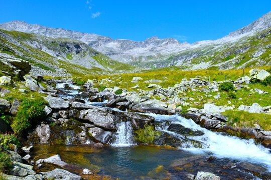 Torbach Alpine stream flowing through P&ouml;llatal grass and rock covered mountain valley in High Tauern, Carinthia, Austria