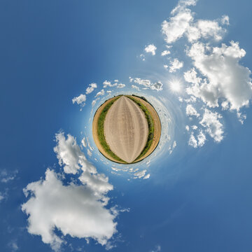simple little tiny planet without buildings in blue sky with sun and beautiful clouds. Transformation of spherical panorama 360 degrees. Spherical abstract aerial view. Curvature of space.