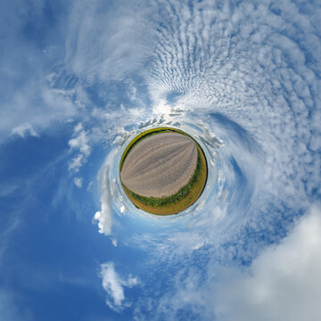 simple little tiny planet without buildings in blue sky with sun and beautiful clouds. Transformation of spherical panorama 360 degrees. Spherical abstract aerial view. Curvature of space.