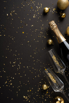 Elegant New Year 2027 celebration with champagne and gold confetti on vertical black background