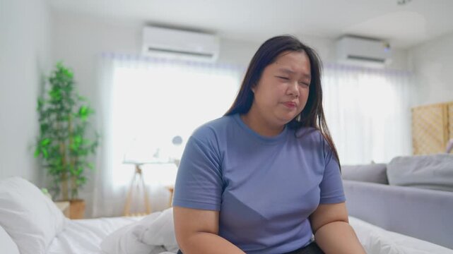 Asian plus-size woman covering nose with tissue while sneezing in morning. 