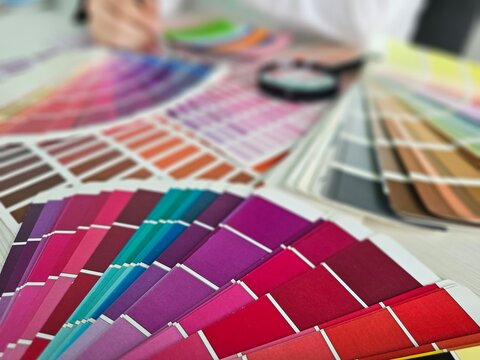 Color swatches are spread on a table as a person selects shades