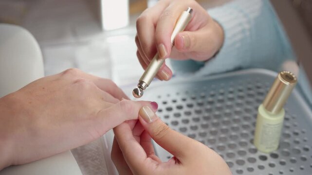 Close up of nail technician drying gel nail polish on female fingernails.