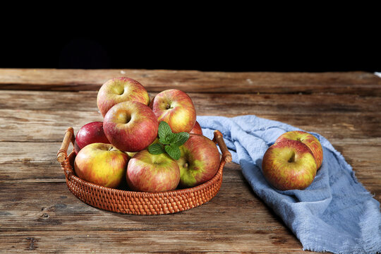 Fresh Organic Apples in Wicker Basket on Rustic Wood Table with Blue Linen Cloth